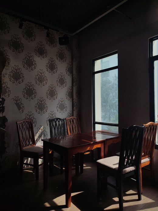 Dining room corner with ornate patterned wallpaper and dark wood chairs