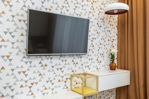 Living-room wall in a beige-and-gold geometric wallpaper with a wall-mounted television