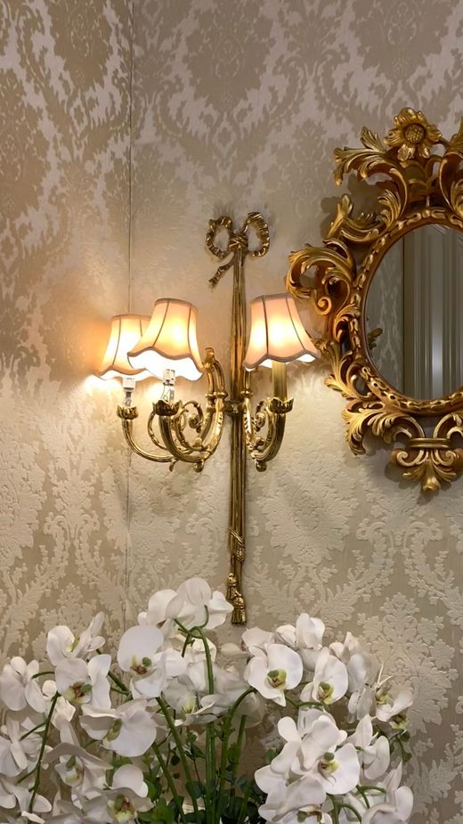 Detail of a vintage floral wallpaper with a gilded sconce and mirror