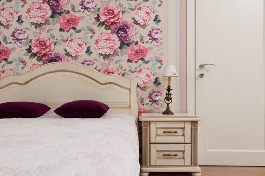Traditional bedroom with rose-patterned wallpaper and a classic bed