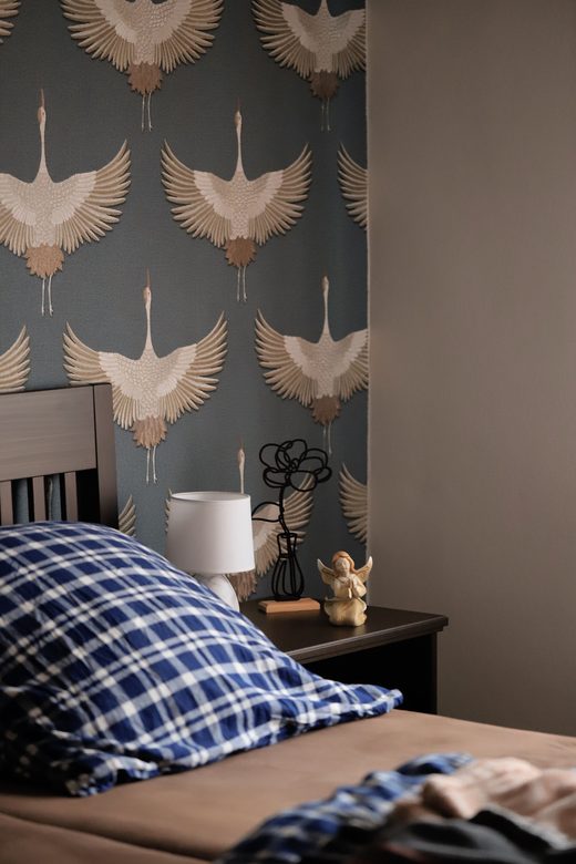 Bedroom feature wall in dusty-blue wallpaper with a flying-crane botanical motif